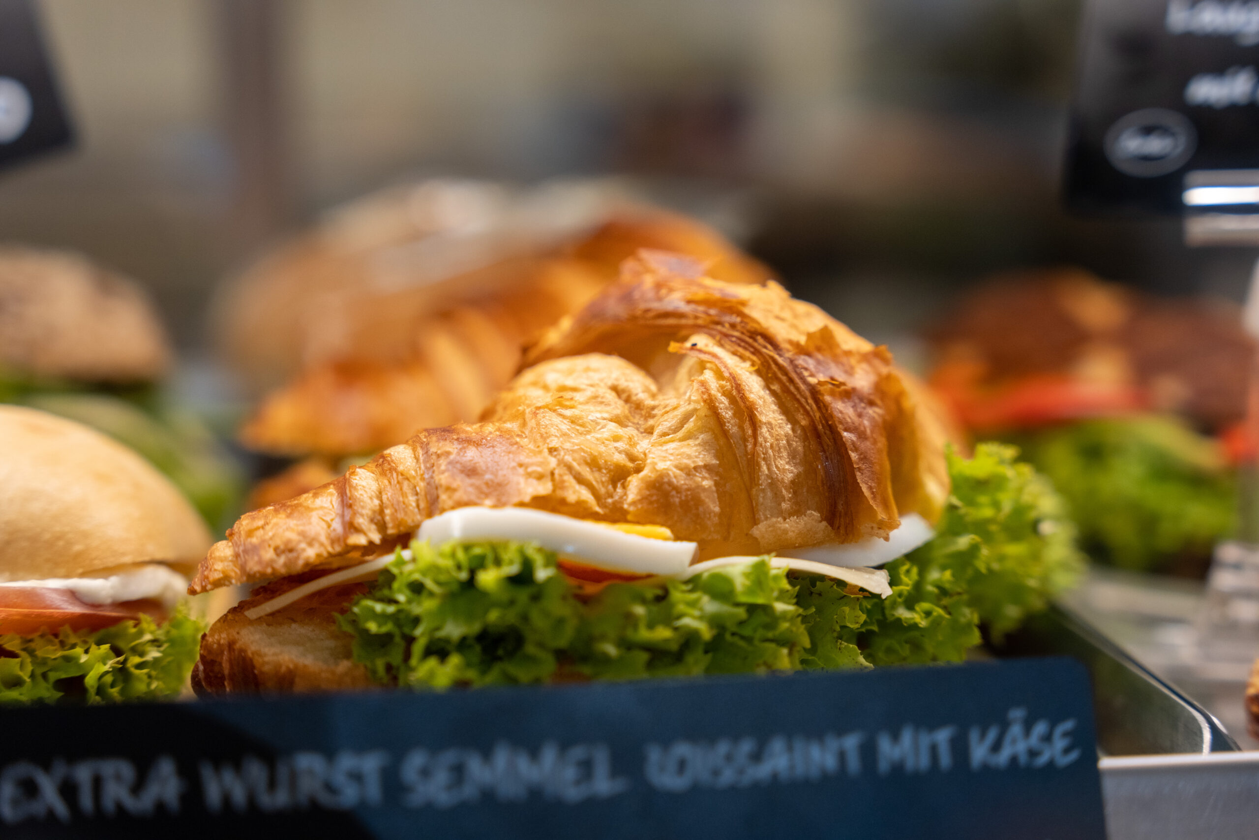Belegte Croissants mit Salat, Tomaten und Käse in der Audimax-Auslage.