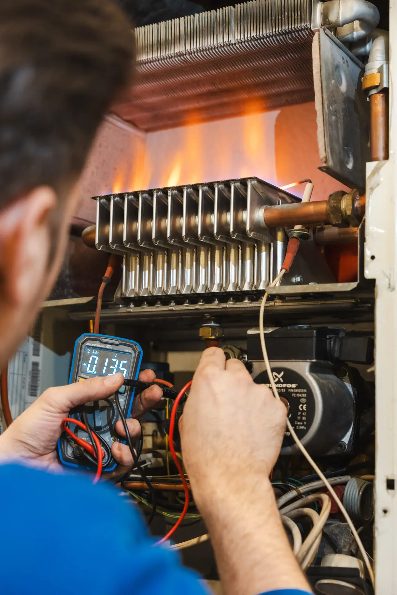 Installateur prüft eine geöffnete Gastherme mit einem Messgerät.