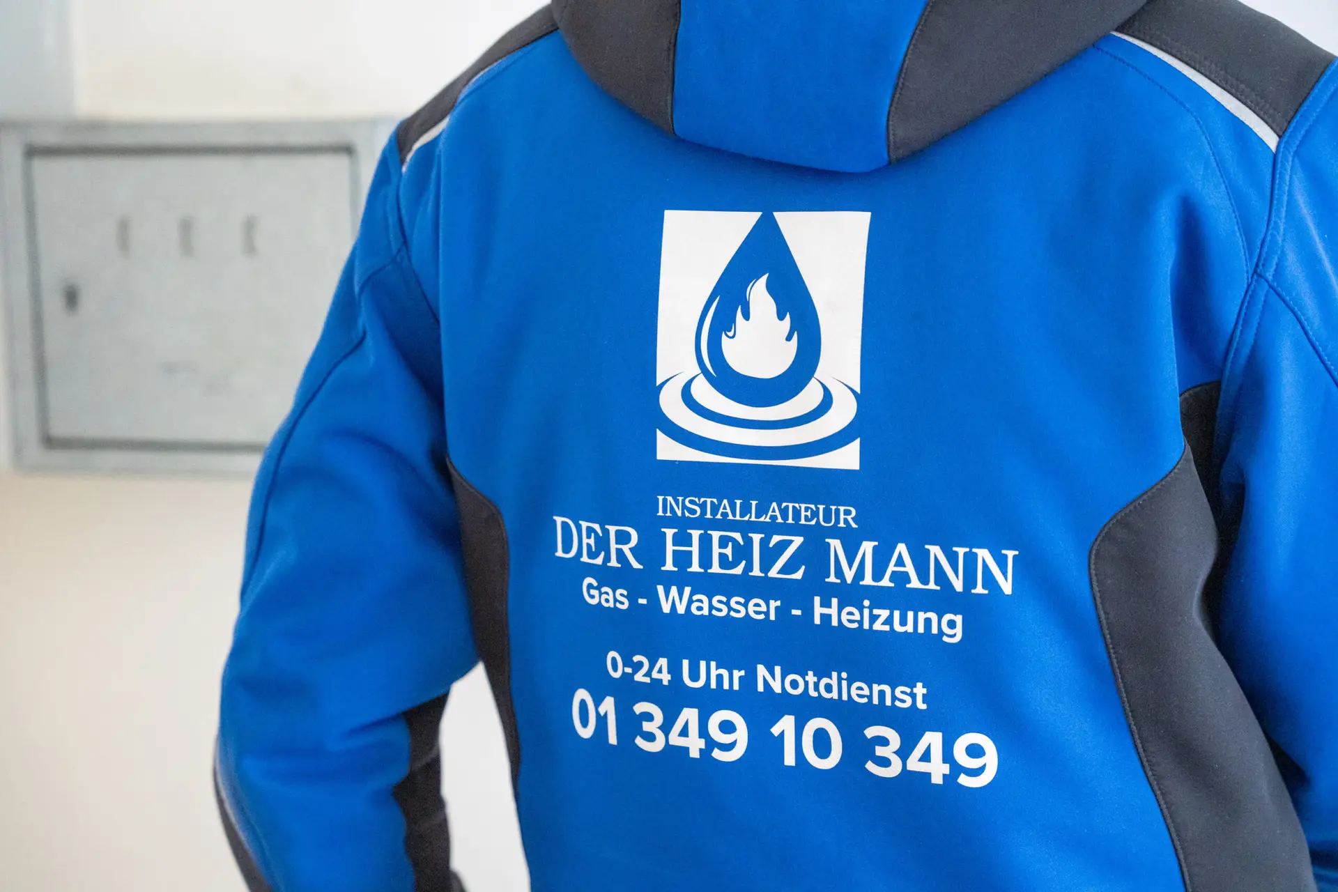 Logo von Der Heiz Mann auf einer blauen Arbeitsjacke.