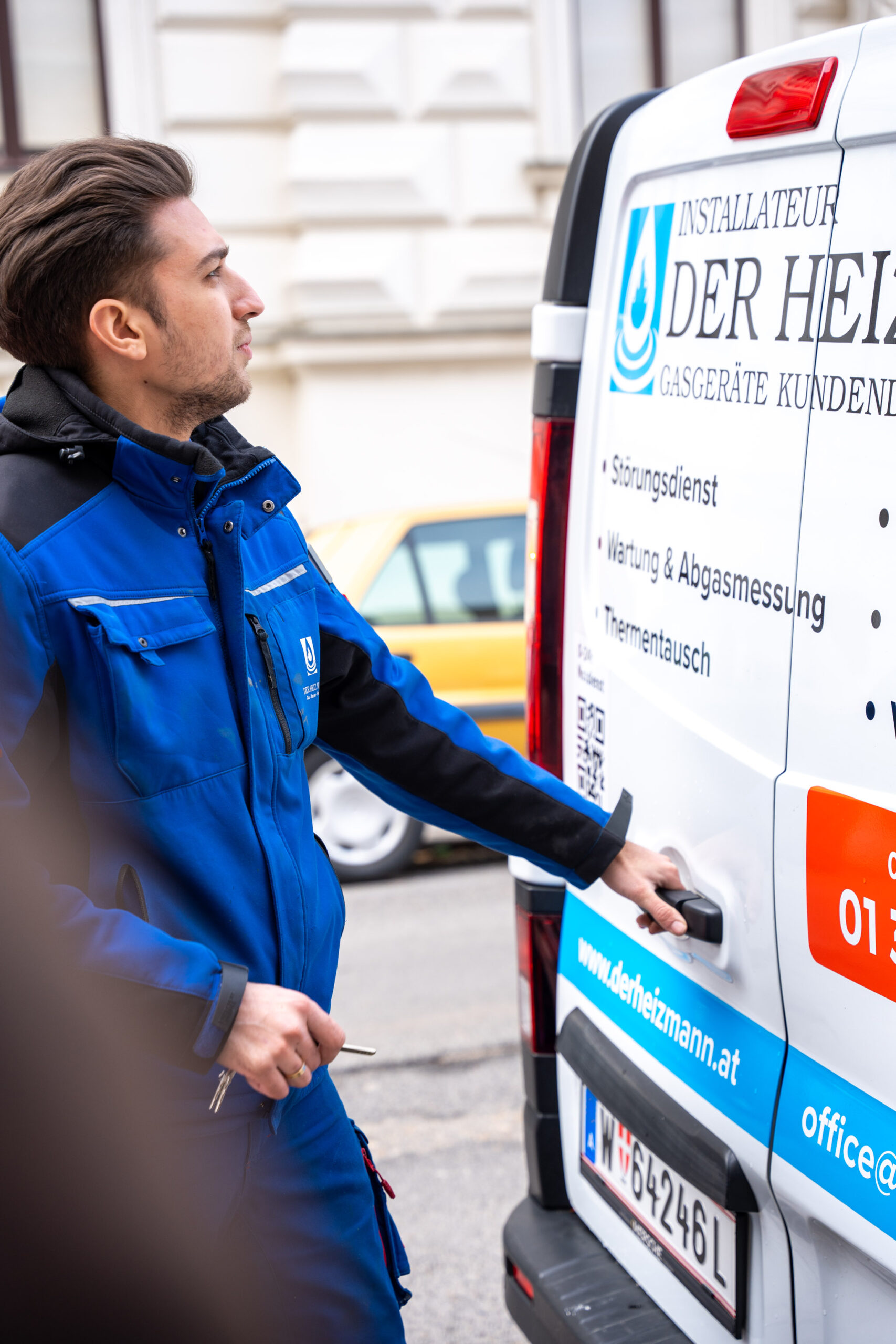 Mitarbeiter neben der geöffneten Hecktür des Installateurfahrzeugs.