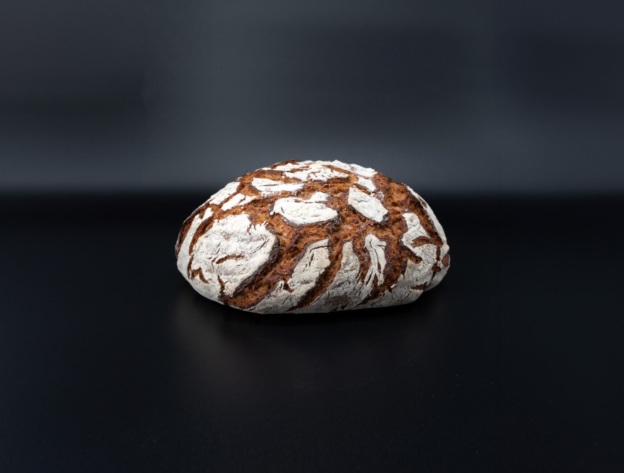 Bemehlter Brotlaib der Prindl Feinbäckerei auf dunklem Hintergrund.