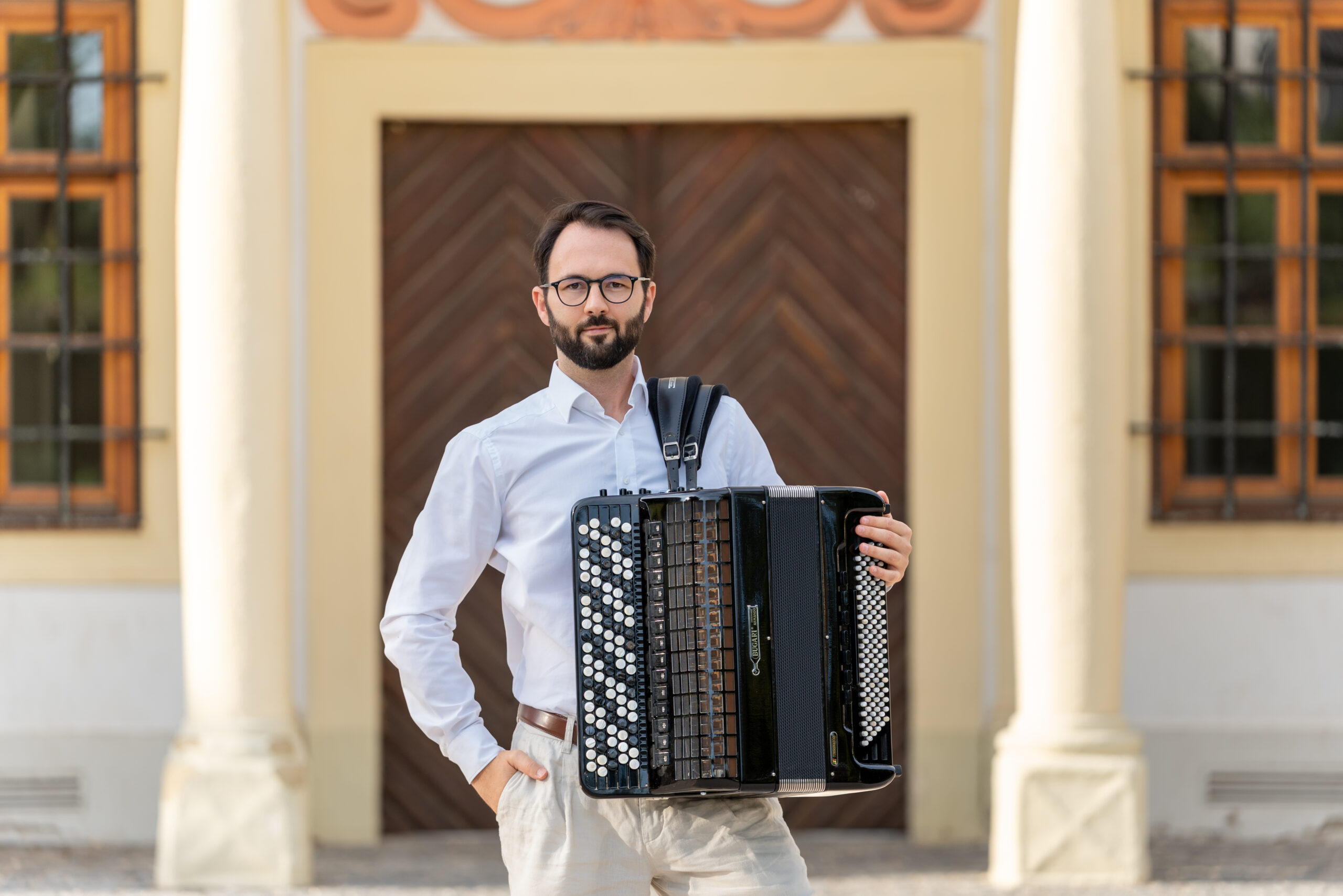 Nikola Djoric mit Akkordeon vor einer Holztür.