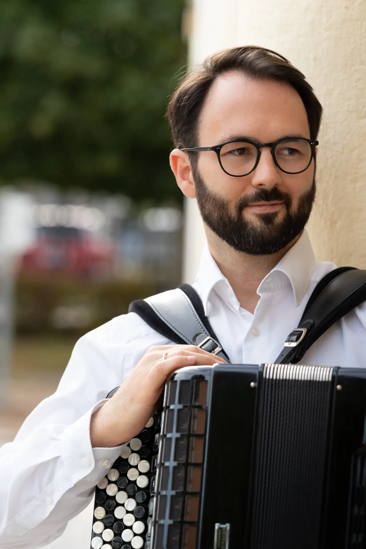 Nikola Djoric mit Akkordeon neben einer Steinsäule.